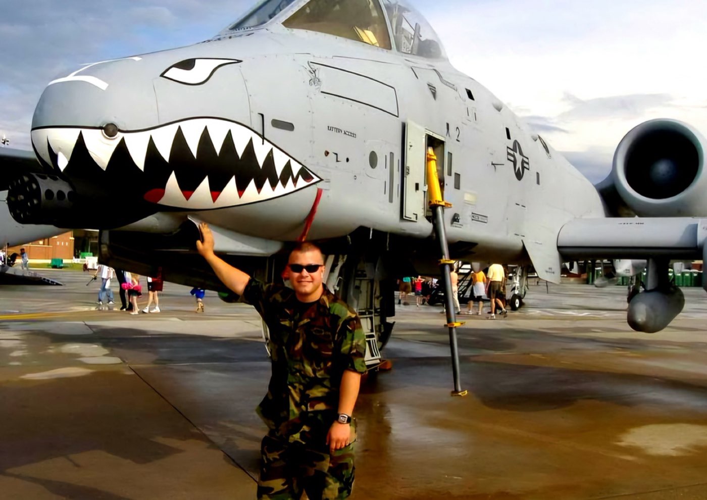 Brian Dimoff in camouflage posing beside the painted nose of an A-10 Warthog
