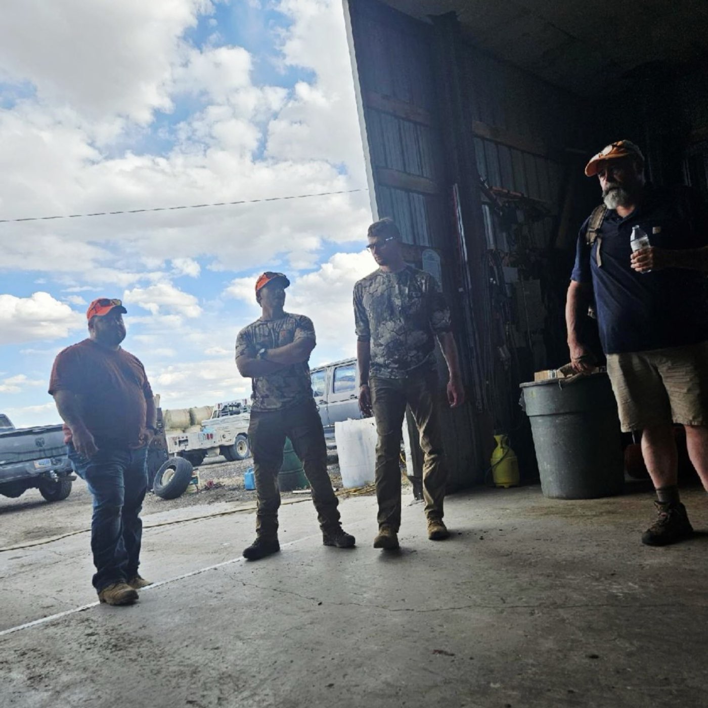 A group of Veterans gathered at the open door of a shop building
